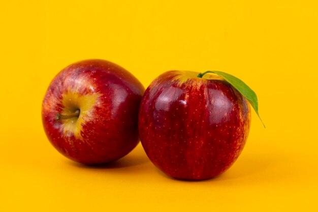 Two red apples isolated on yellow background Two fresh apples fruits used for healthy food concept with clipping path and full depth of field