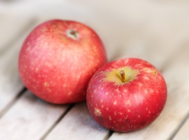 Two red apples on a wooden table indoors Eat healthy and watch your diet Fruit contains essential vitamins to boost your immunity Closeup of a delicious snack vegans and vegetarians can enjoy