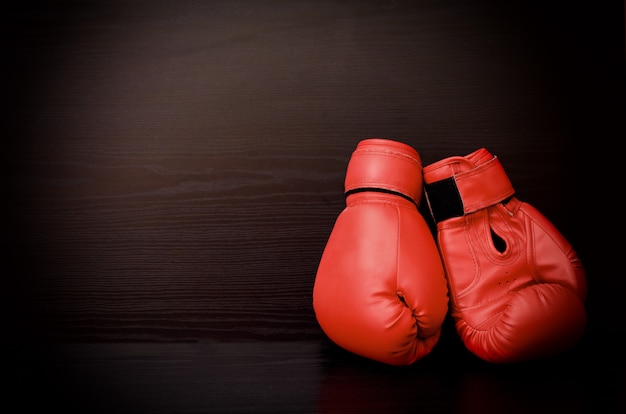 Two red boxing gloves on the side of the frame on a black background