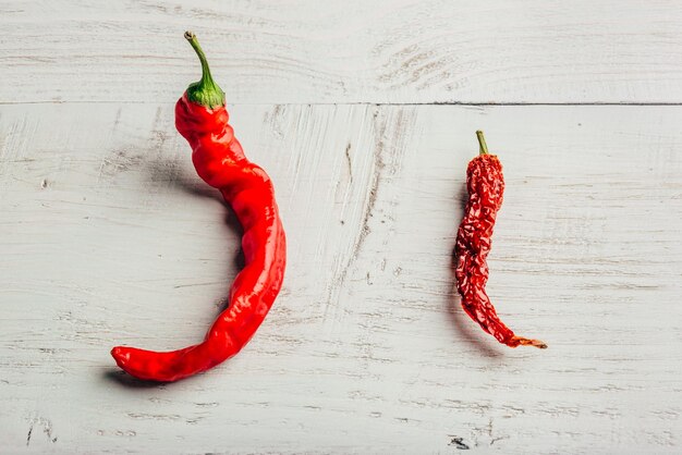 Photo two red chili peppers on wooden background