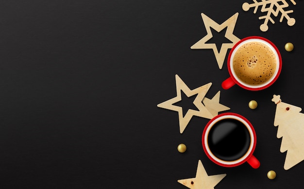 Two red cup of coffee and christmas decoration on black paper background
