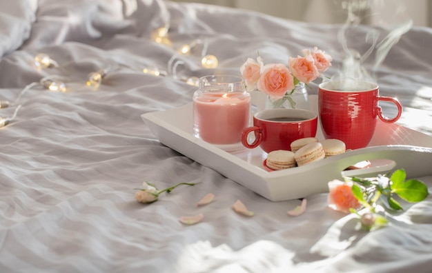 two red cups of coffee and flowers on bed