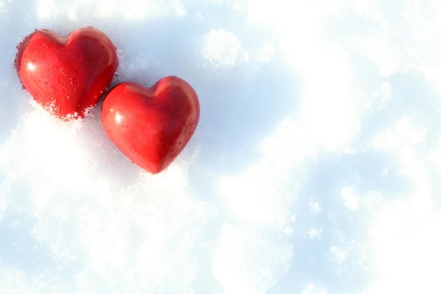 Two red frozen heart on snow background