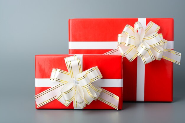 Two red gift box with a white ribbon and a bow