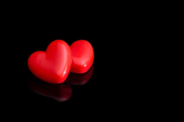 Two red hearts on a black background.