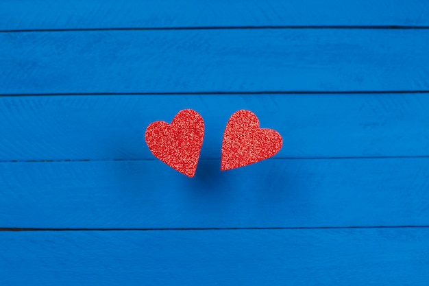 Two red hearts on blue wooden background, close-up,