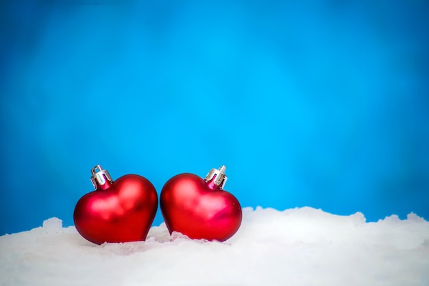 Two red hearts, Christmas toys in the snow on a blue background