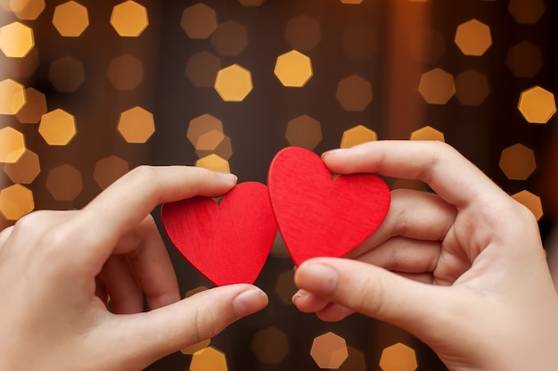 Two red hearts in hand on bokeh background.