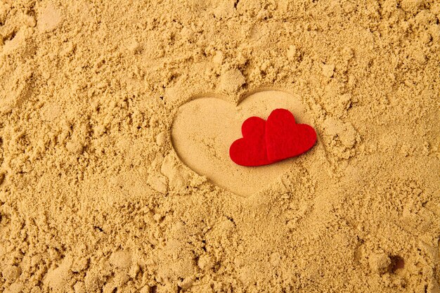 Two red hearts on the summer beach sand