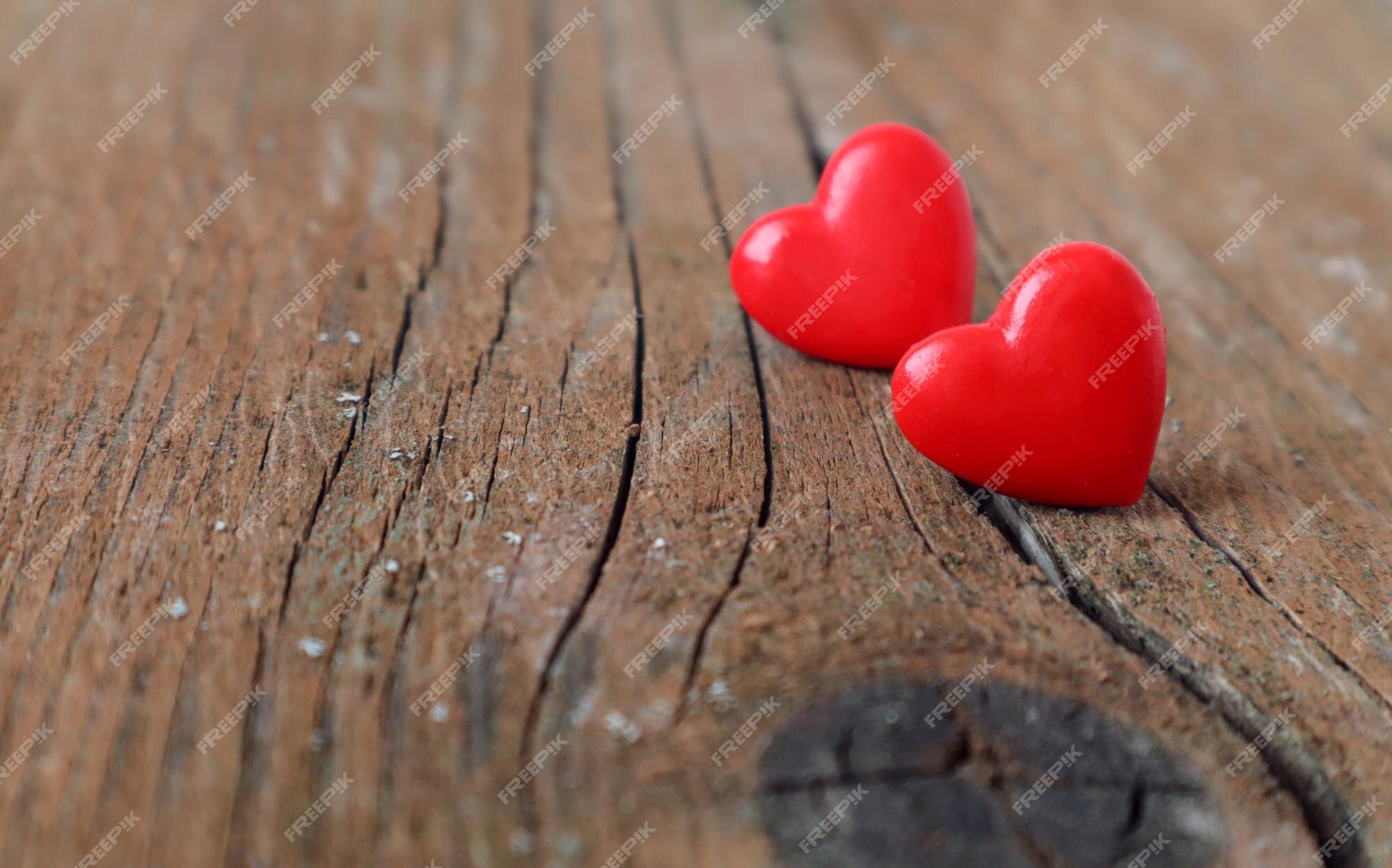 Premium Photo | Two red hearts on a wooden background a crack in the center  a side view a closeupthe concept of a complex family relationship