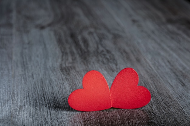 Two red hearts on wooden background.