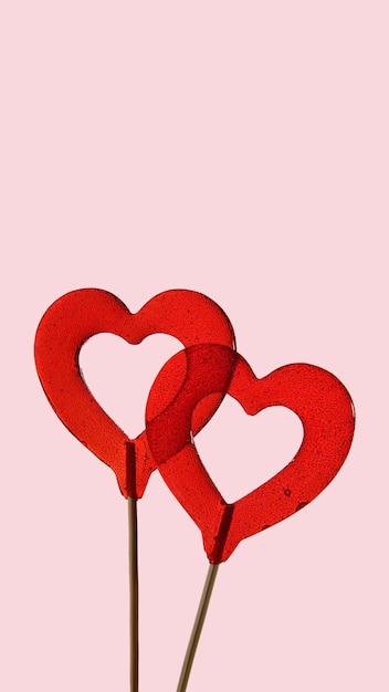 Two red heartshaped lollipops on a pink background Love Vertical banner for Valentines Day