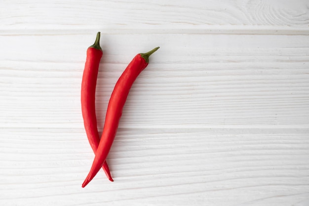 Two red hot peppers on a light background