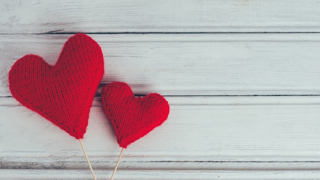 Two red knitted hearts on wooden background . the concept of Valentine's day