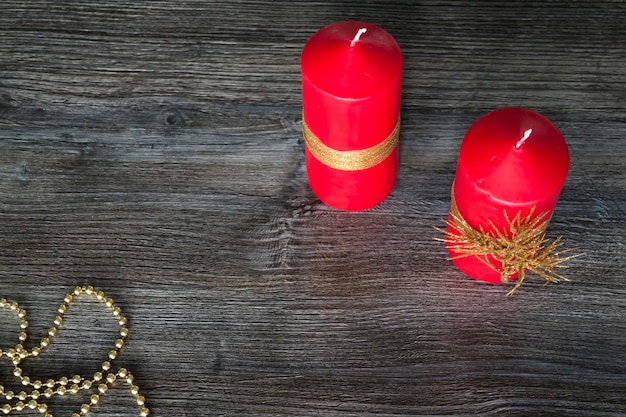 Two red New Year candles with gold decorations on a wooden background