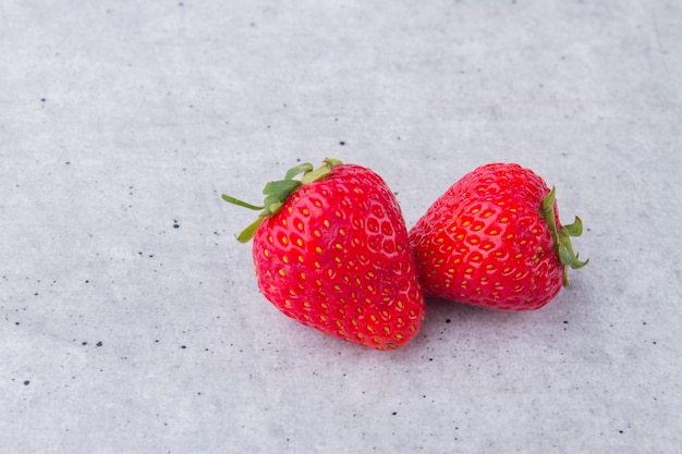 Two red raw fresh strawberries on white background