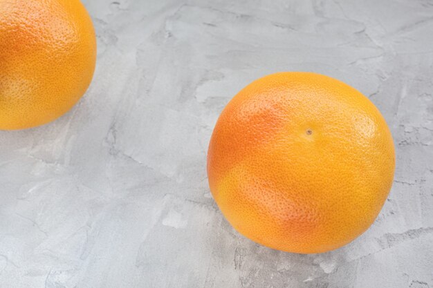 Two red ripe grapefruits on gray