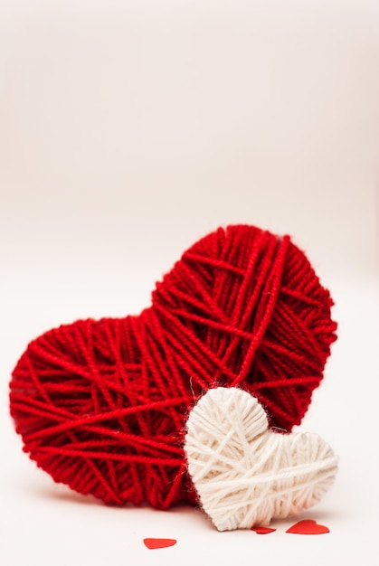 Two red and white clews in shape of heart made from yarn