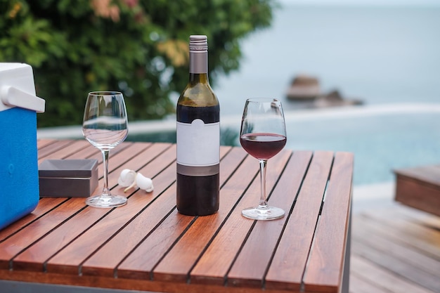 Due bicchieri di vini rossi vicino alla piscina. concetto di viaggio estivo, vacanze, vacanze e buon fine settimana