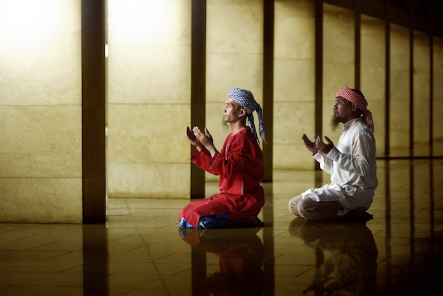 Two religious muslim man praying together