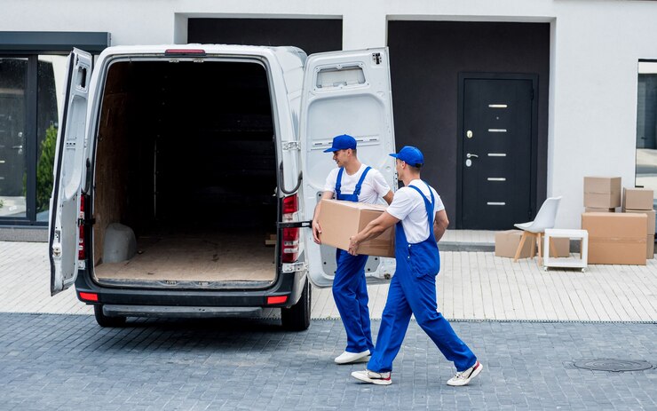 Photo two removal company workers are loading boxes and furniture into a minibus