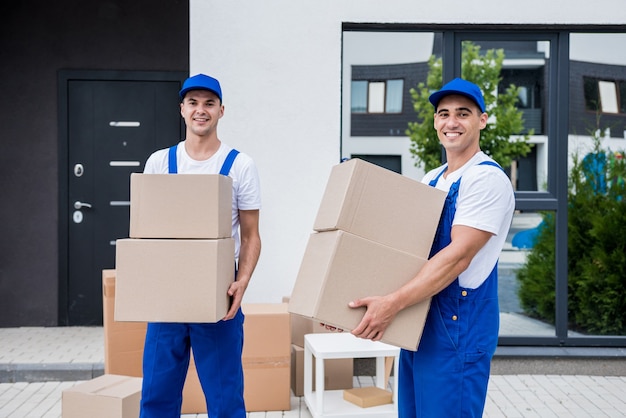 Two removal company workers are loading boxes into a minibus