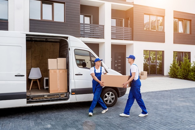 Two removal company workers are loading boxes into a minibus