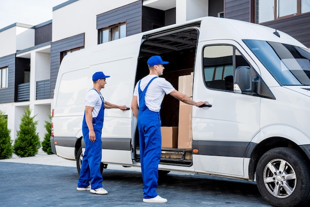 Two removal company workers are loading boxes into a minibus