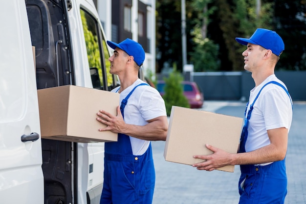 Two removal company workers are loading boxes into a minibus