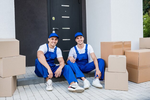 Two removal company workers have a break while sitting on the step