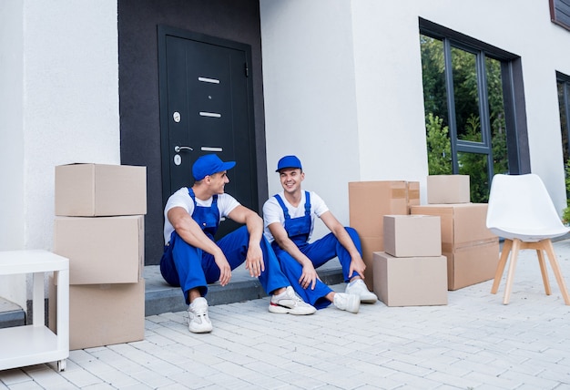 Two removal company workers have a break while sitting on the step