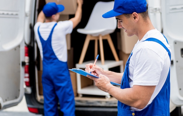 Two removal company workers unloading boxes from minibus into new home