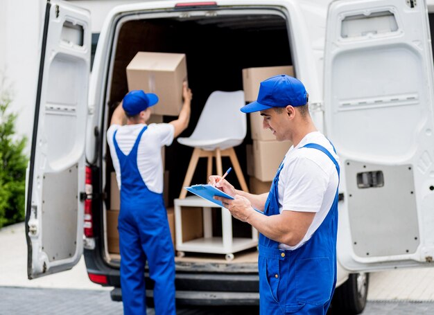 Two removal company workers unloading boxes from minibus into new home