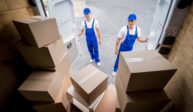 Two removal company workers unloading boxes from minibus