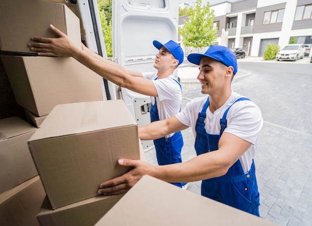 Two removal company workers unloading boxes from minibus