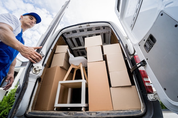 Two removal company workers unloading boxes and furniture from\
minibus