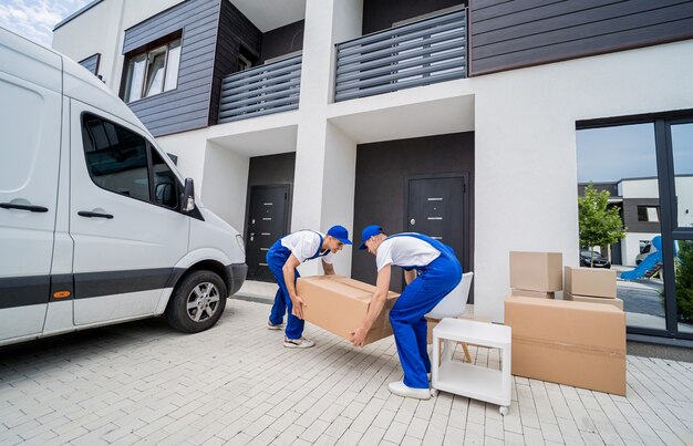 Photo two removal company workers unloading boxes and furniture from minibus