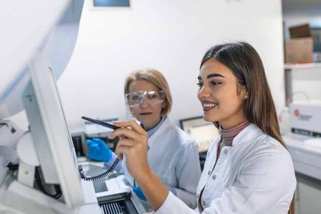 Two Research Scientists Programm Medical Equipment with Tablet Computer Team of Professionals Doing Pharmaceutical Research in Modern Laboratory