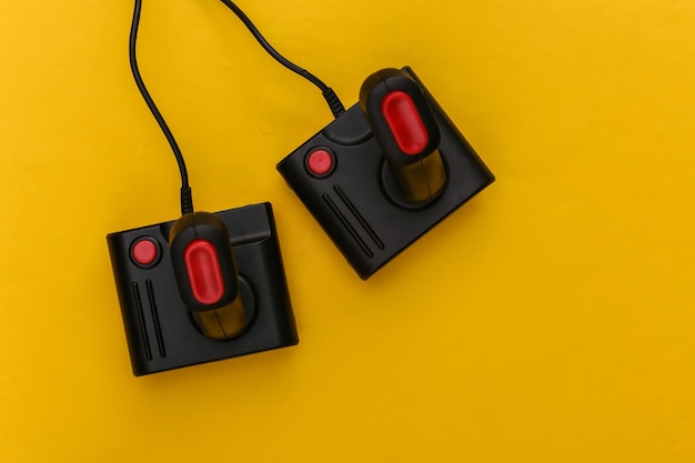 Two retro joysticks on yellow background. Gaming, video game competition. Top view, minimalism