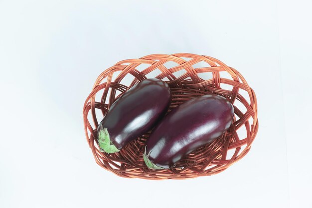 Two ripe eggplant in a wicker basketisolated on white