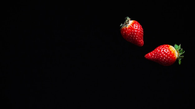 Two ripe juicy red strawberries fly fall in the air