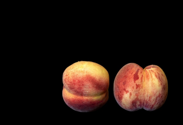 Two ripe peaches on black background