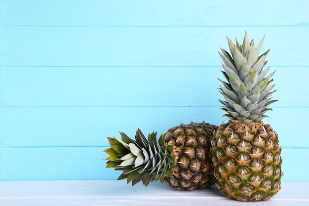 Two ripe pineapples on a blue background with copy space