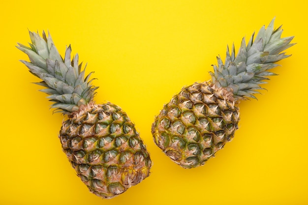 Two ripe pineapples on a yellow background