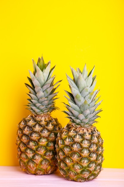 Two ripe pineapples on a yellow background