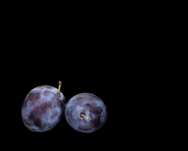 Two ripe plums on a black backgroundxA