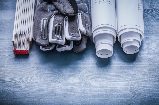 Two rolls of blueprints safety gloves and wooden meter