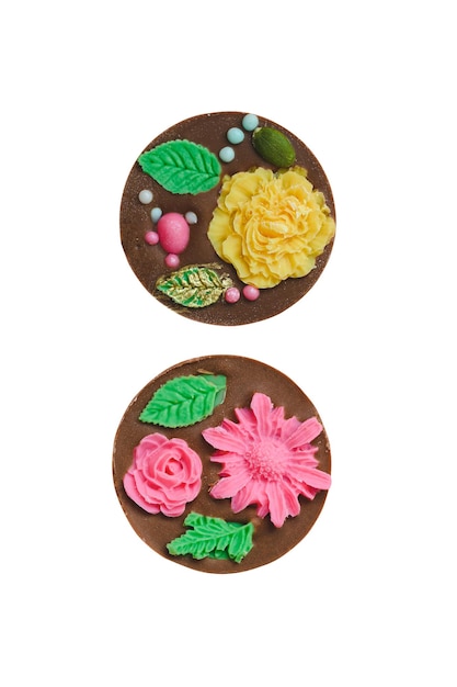 Two round handmade chocolate candies decorated with leaves and flowers isolated on white