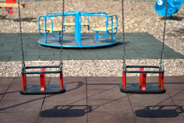 Foto due altalene di gomma pesano su una catena parco giochi in una giornata di sole ombra dall'altalena i posti sull'altalena sono liberi non ci sono bambini nel parco giochi