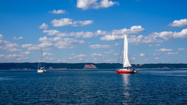 Two Sailing Boats, White and Red, on the River.